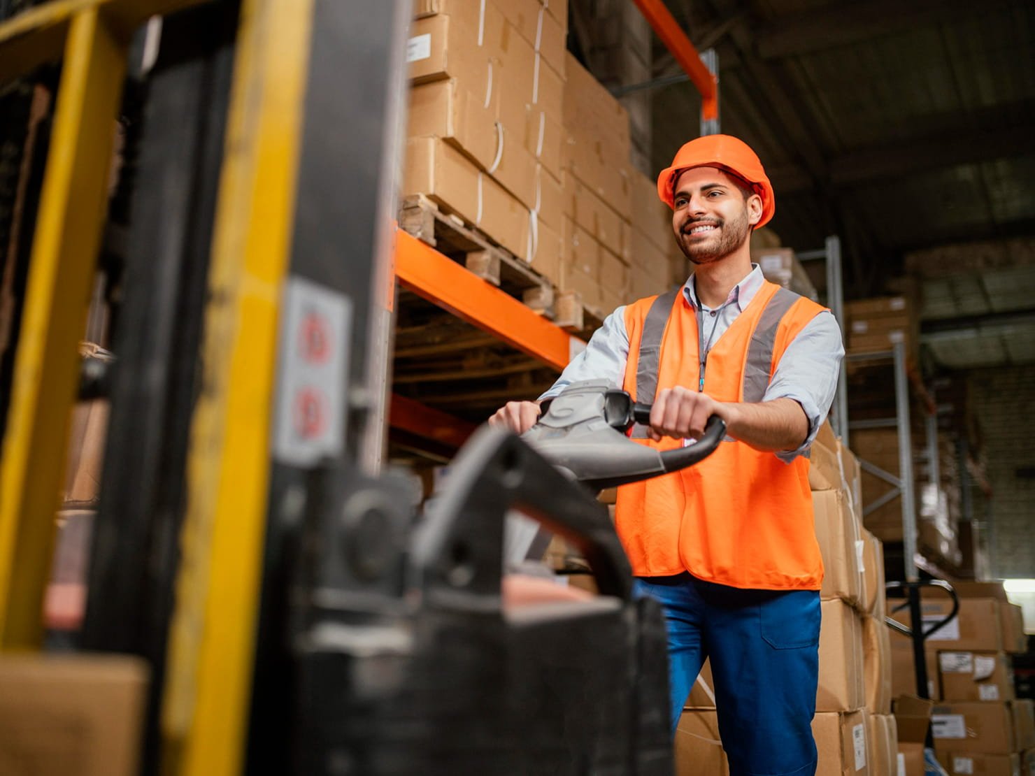 Operador de logística utilizando paleteira elétrica em armazém com caixas organizadas em estoque